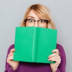 Woman hiding face with book